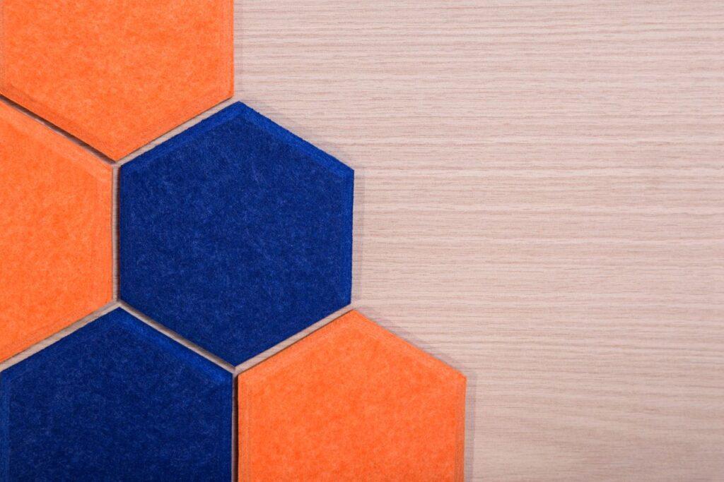 Hexagonale Schallabsorber aus Filz in Blau und Orange, ideal zur Schallreduzierung und als stilvolles Wanddesign.